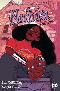 Cover of Nubia: Real One. Nubia, a young Black woman, sits on a curb in a red Wonder Woman shirt and Wonder Woman cuffs. Her hands are interlaced in between her legs as she looks at us.