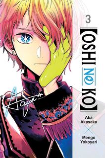 Cover of Oshi no Ko volume 3. Aqua is dressed in an elaborate costume with fringes at the cuff. He is holding one hand over his right eye and he has a bright green glove on his hand. His blue eye with signature star is staring at us. His golden hair is falling around his eye.
